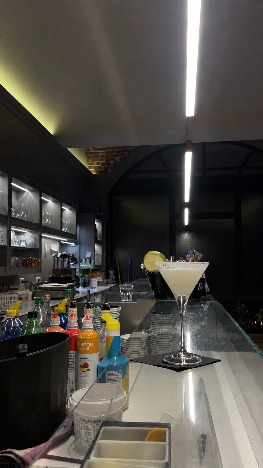 Un cocktail servito in coppa sul bancone del Caffè Grande la sera